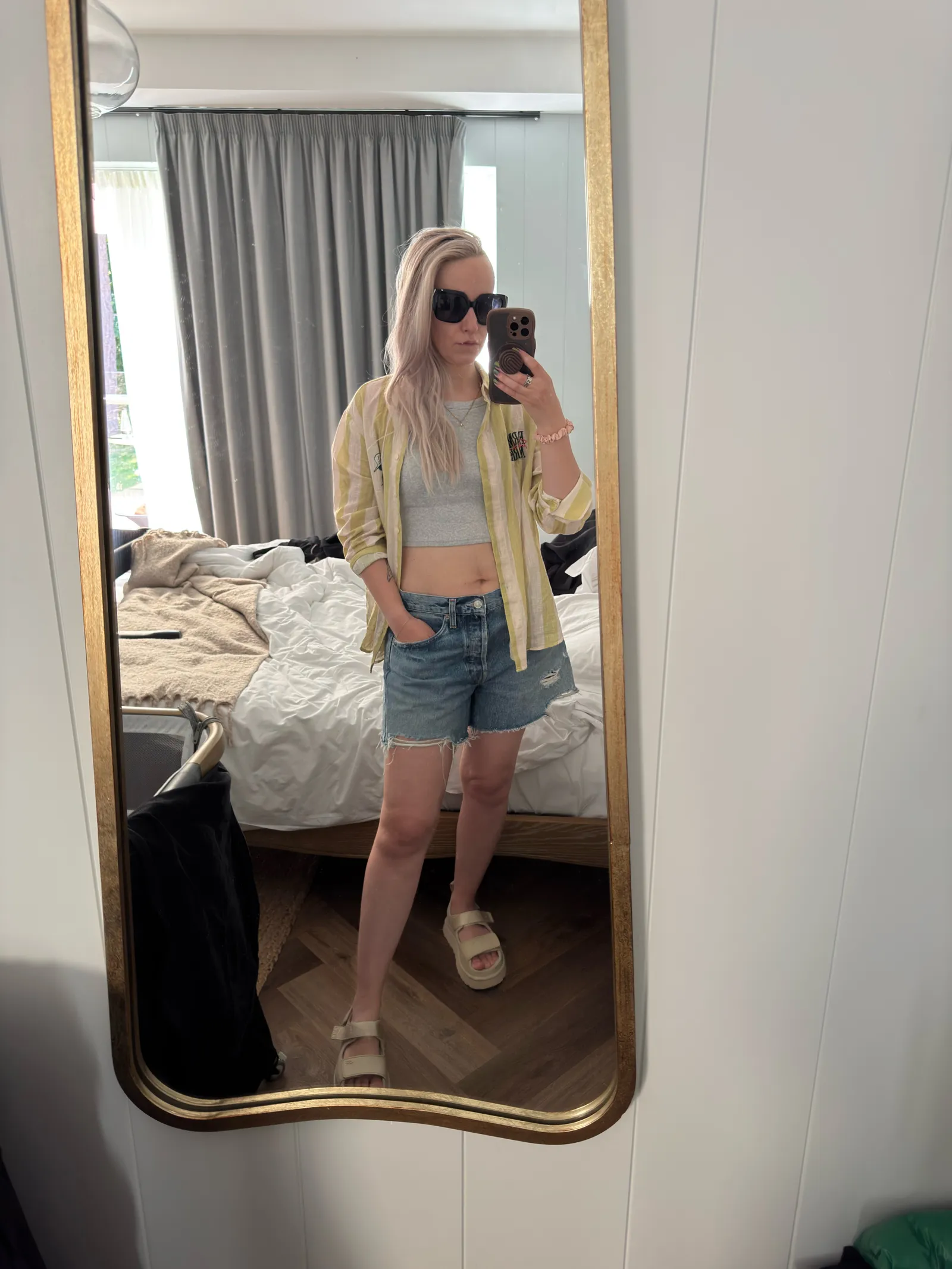 A blonde woman taking a selfie in a hotel room mirror