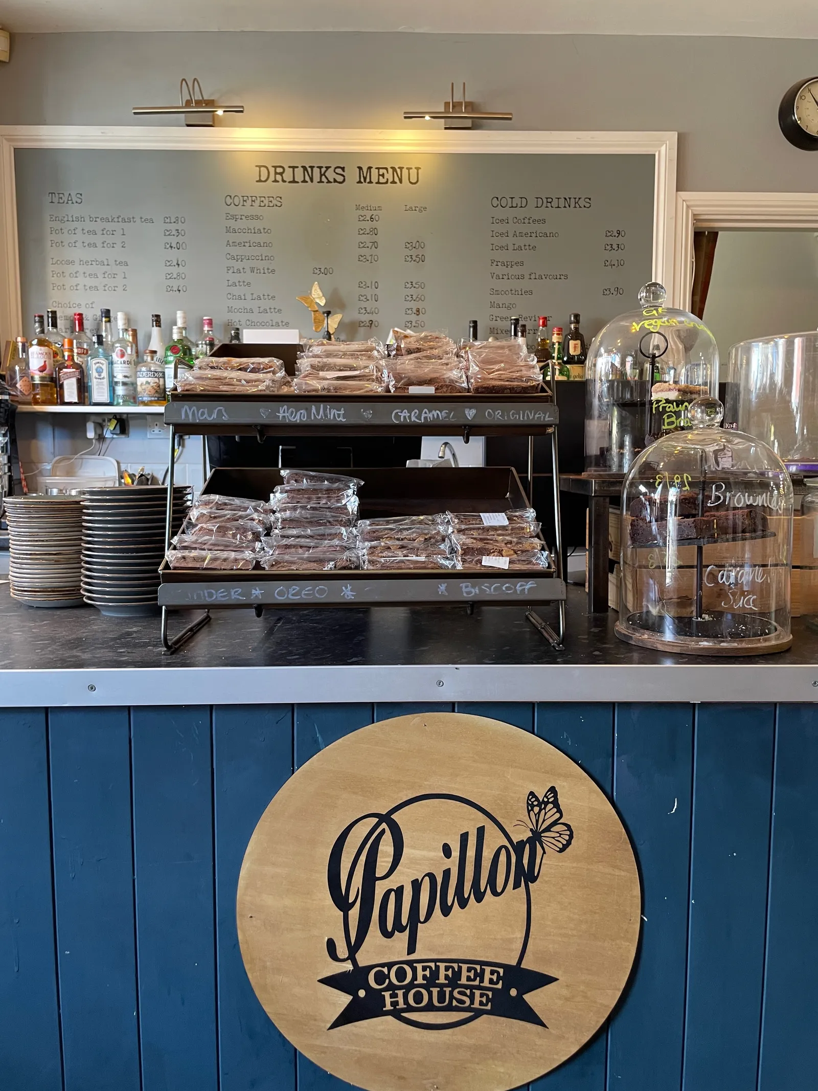 A coffee counter with baked good and menu on the wall